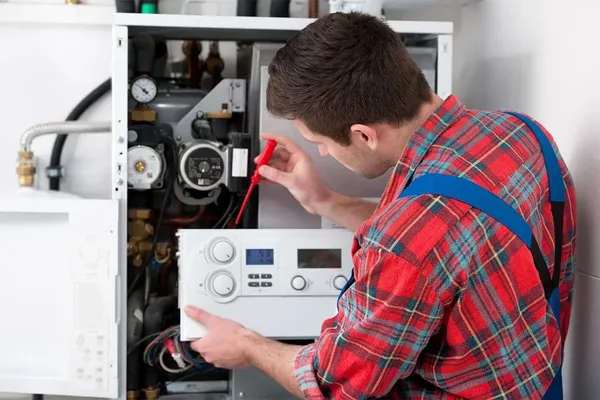 Plumber repairing a water heater, checking components and settings, emphasizing emergency plumbing services in Tulare
